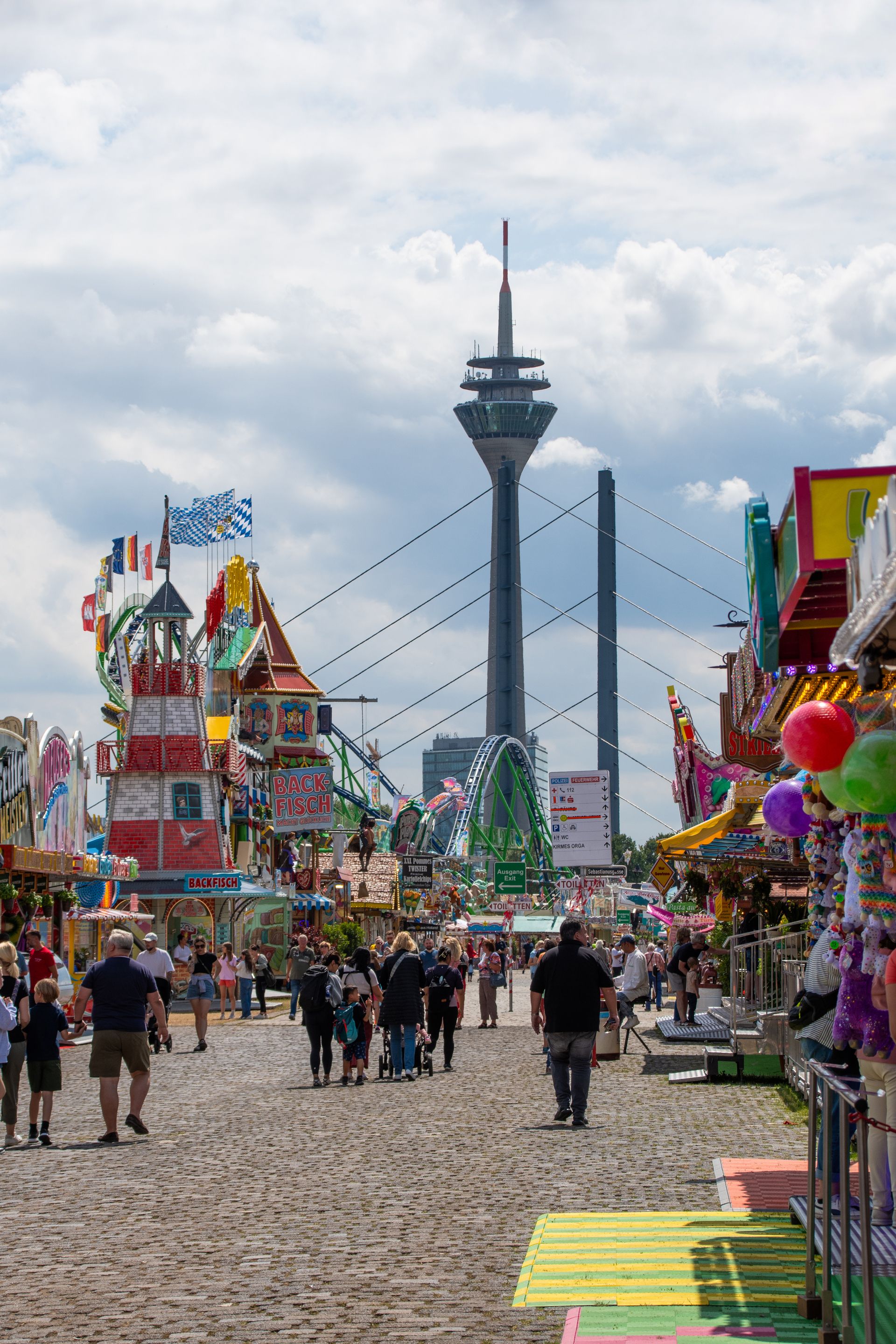 De televisietoren van Düsseldorf rijst op tussen de attracties en eetkraampjes op de Rijnkermis